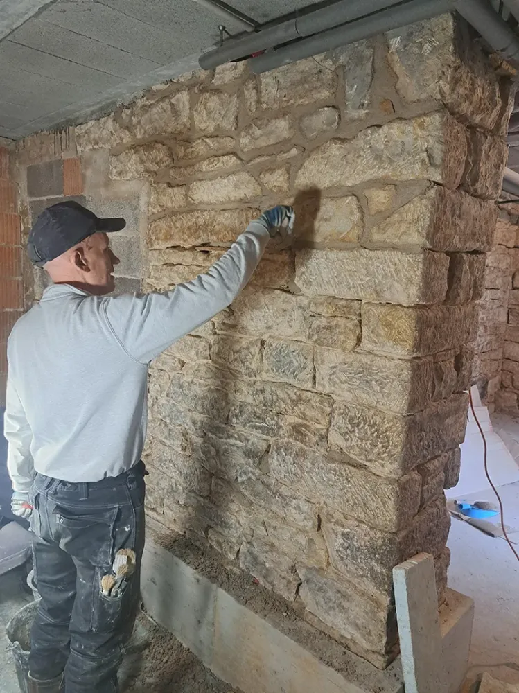Homme devant un mur en pierres